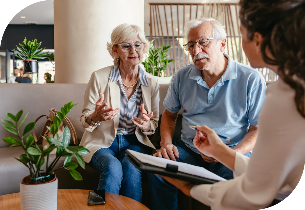Older couple sitting on a couch talking to a woman in a living room