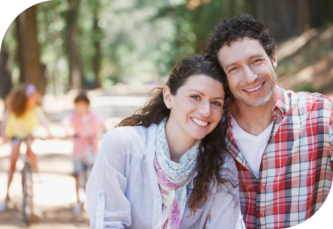 Man and woman at the camera while riding bicycles in the woods